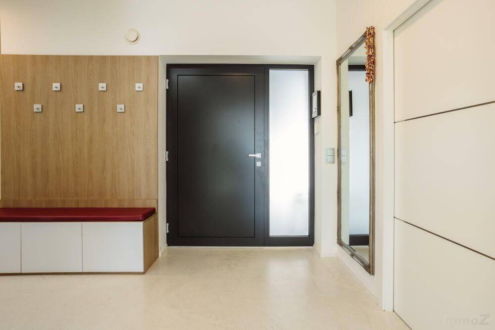 Heller Eingangsbereich mit Garderobe, Sitzbank und großem Spiegel.