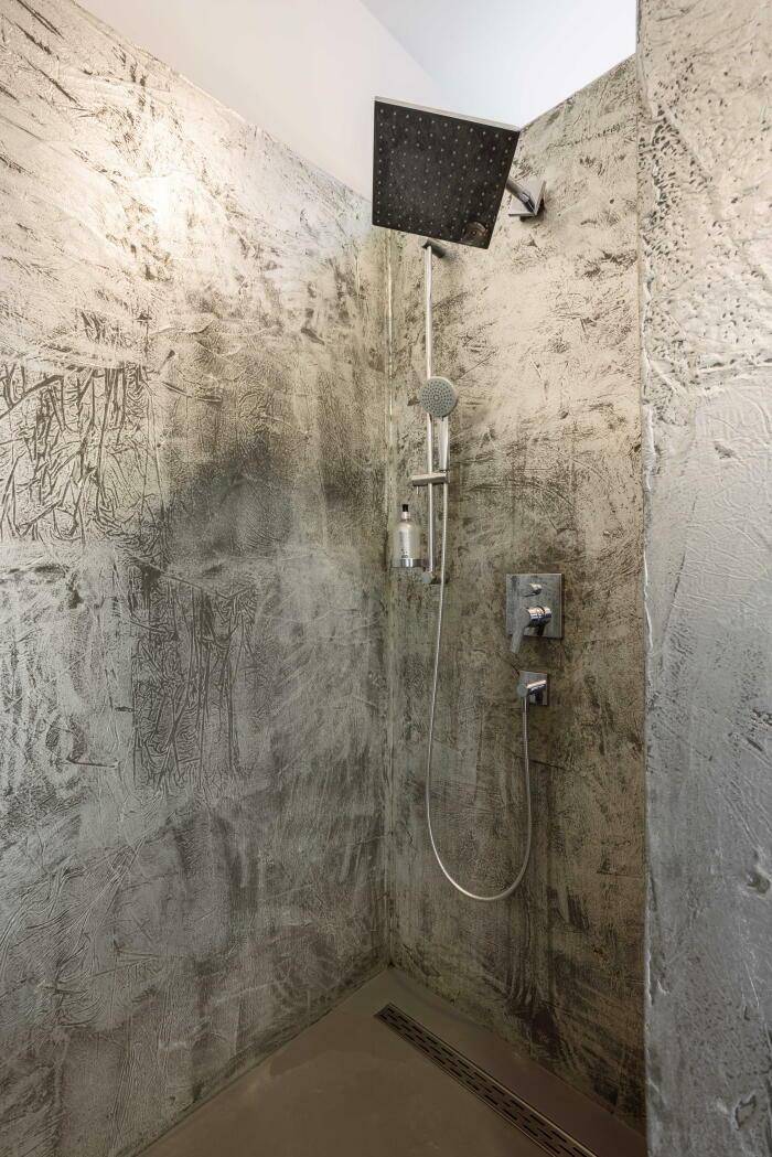 Moderne Dusche mit Regenduschkopf und strukturierten grauen Wänden.