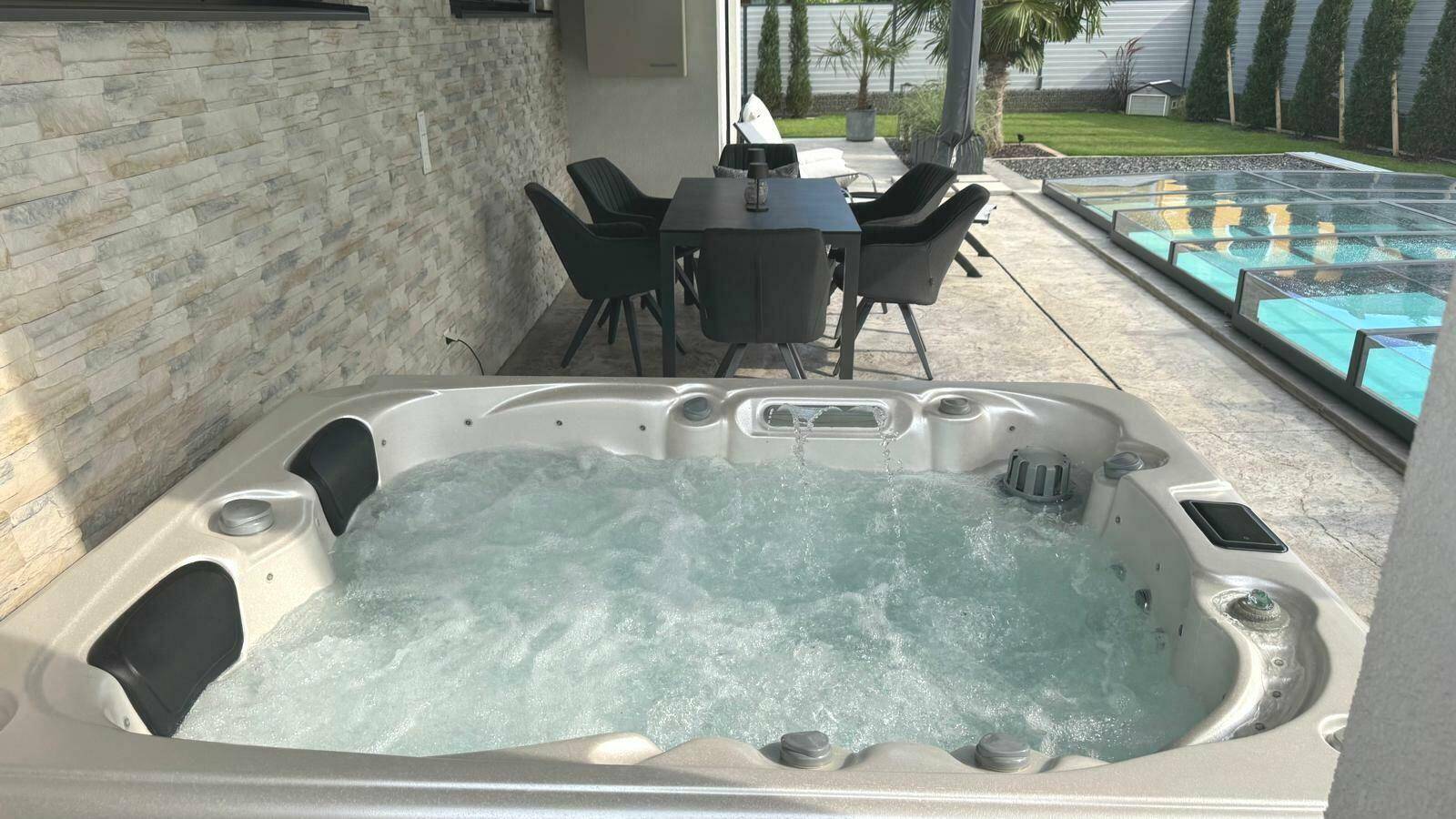 Entspannungsbereich im Freien mit Whirlpool und Esstisch auf der Terrasse.