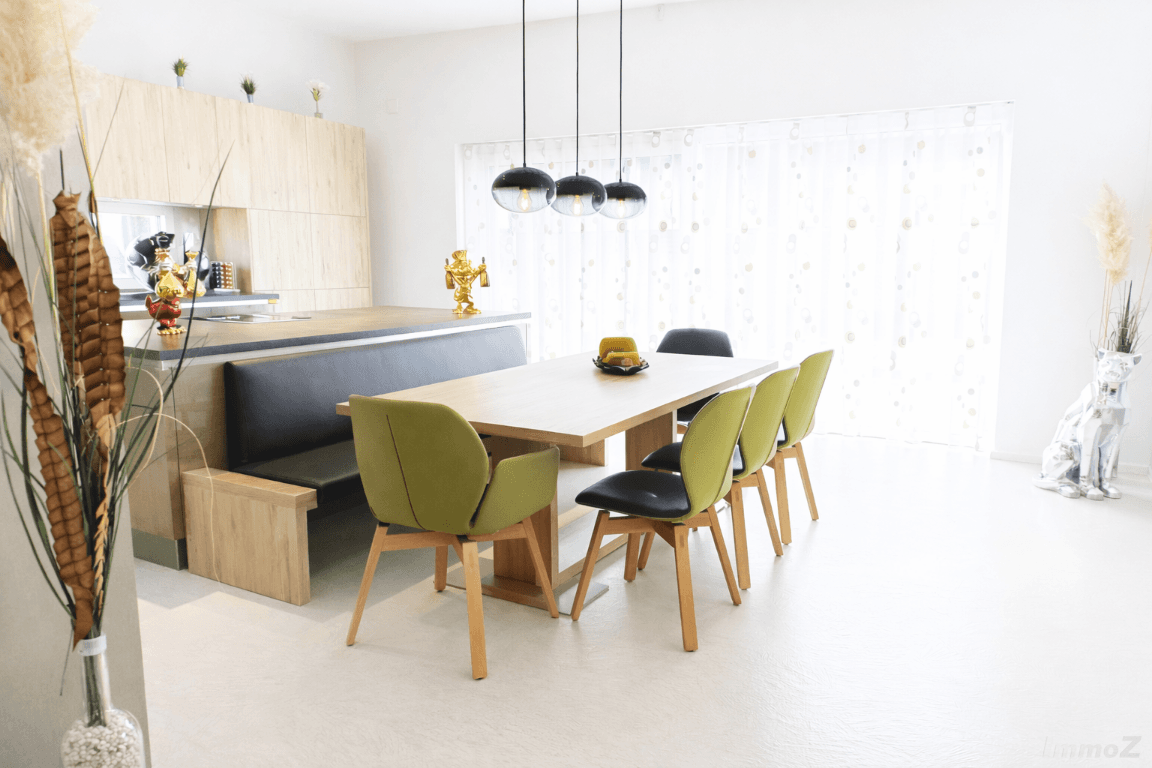 Moderner Essbereich mit Holztisch, Sitzbank und Blick auf die helle Fensterfront.