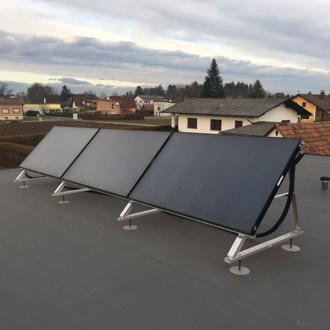 Solaranlage auf dem Flachdach eines Hauses unter bewölktem Himmel.