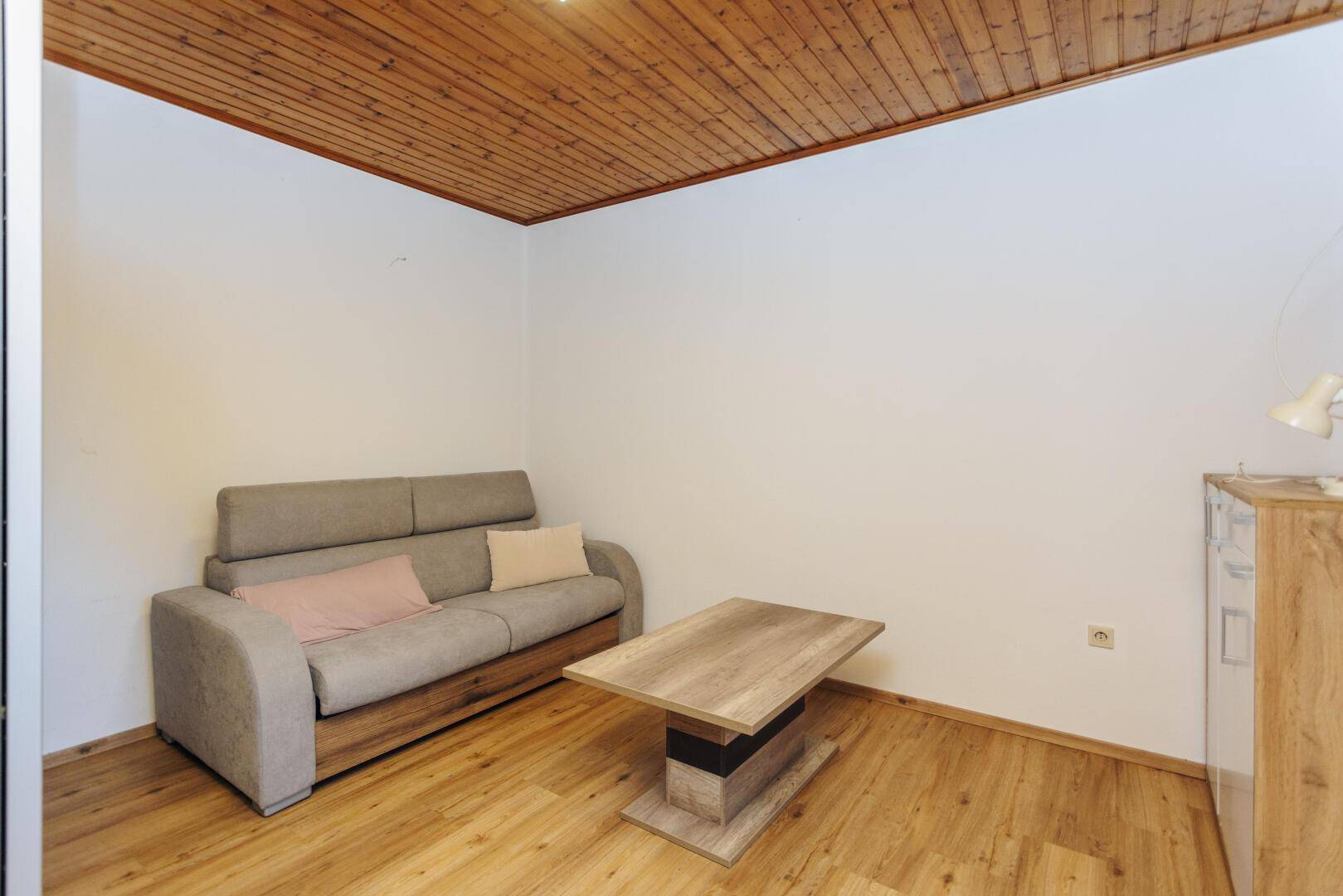 Gemütliches Wohnzimmer mit Sofa, Couchtisch und Holzdecke, ideal zum Entspannen.