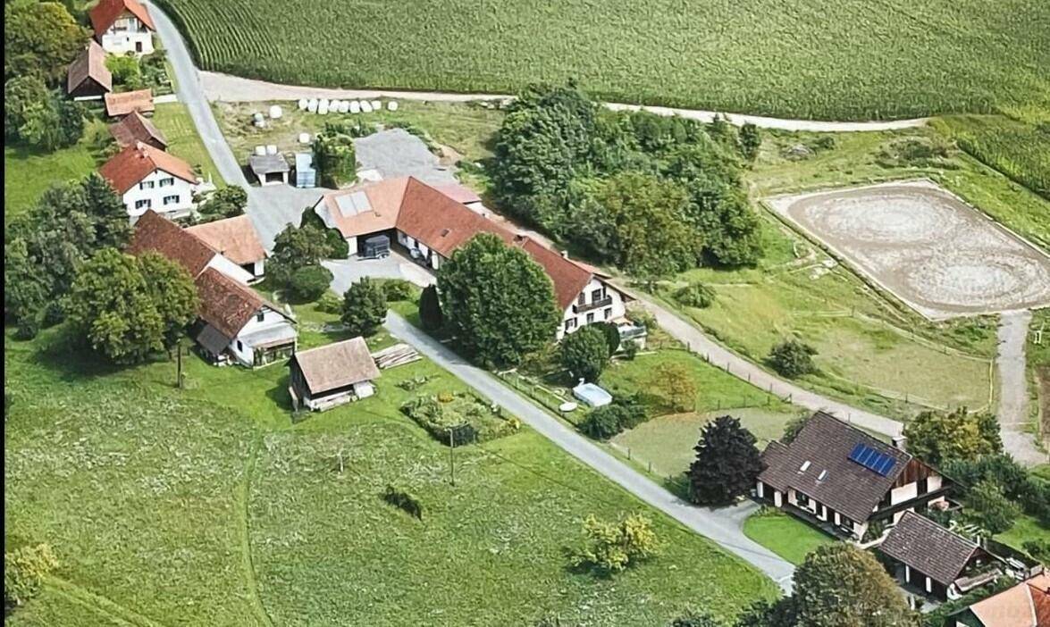 Luftaufnahme eines ländlichen Anwesens mit mehreren Gebäuden, Feldern und Reitplatz.