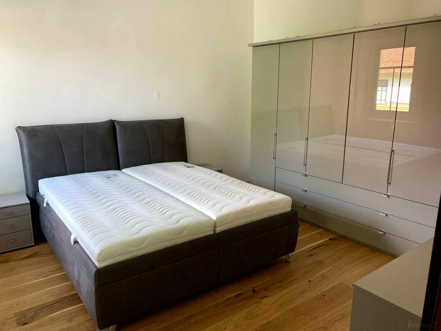 Helles Schlafzimmer mit Doppelbett, großem Kleiderschrank und Holzboden.