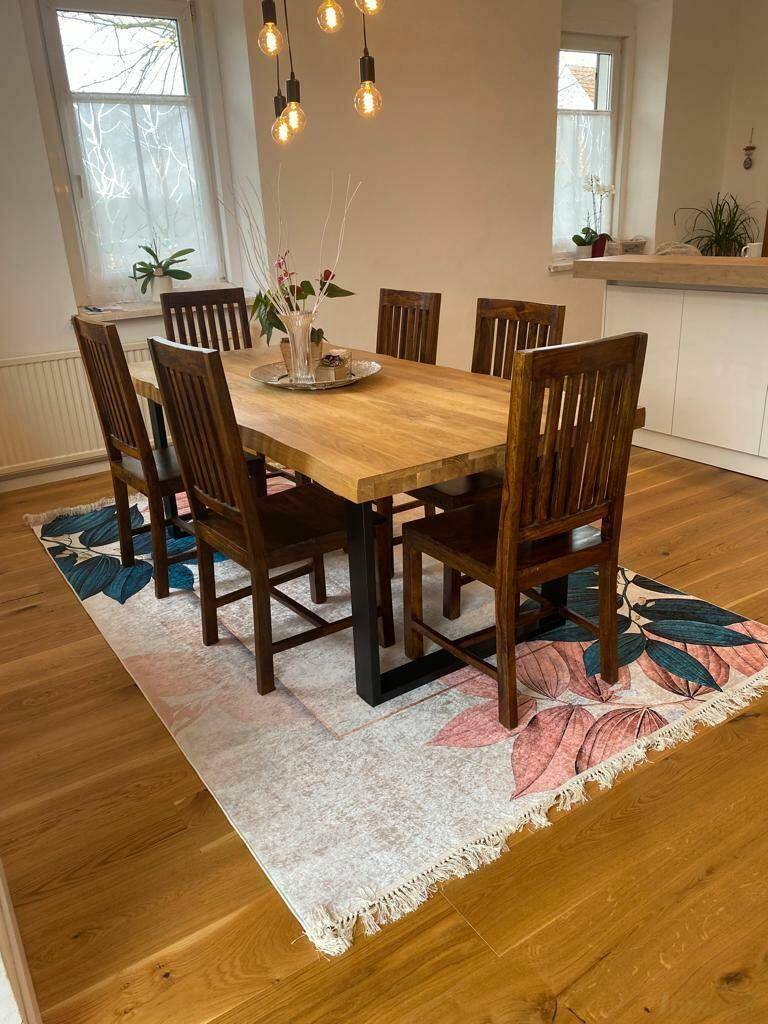 Heller Essbereich mit Holztisch, passenden Stühlen und modernem Teppich auf Parkettboden.