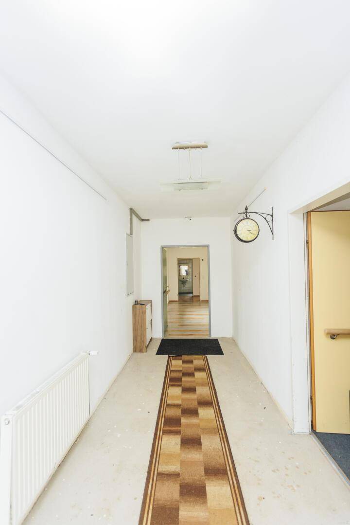 Langer, heller Flur mit Teppichläufer und Türen zu verschiedenen Zimmern.