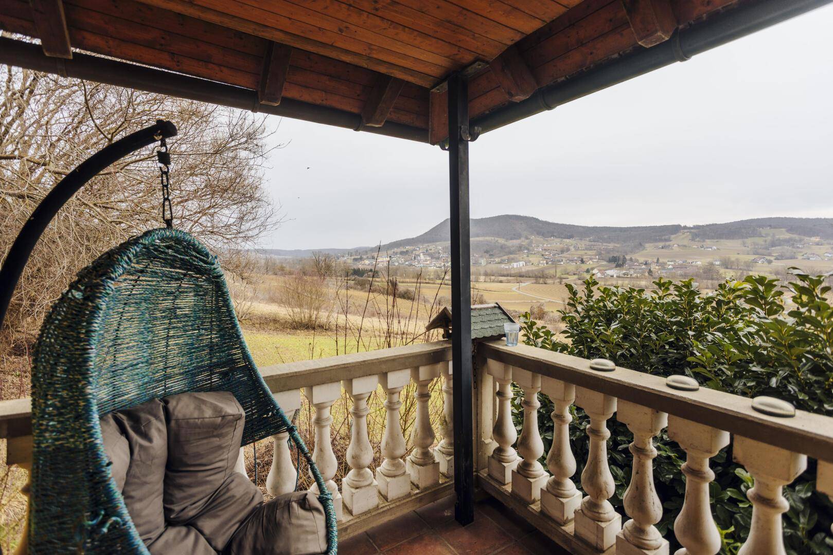 Balkon mit Hängesessel und weitem Blick über die ländliche Umgebung.