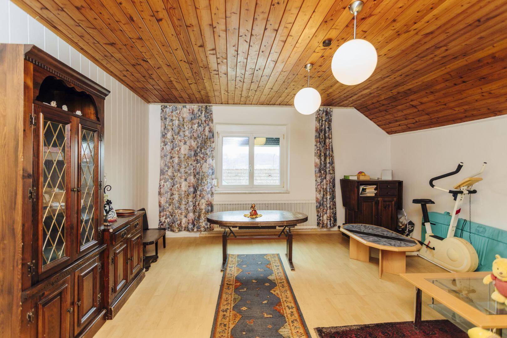 Gemütliches Wohnzimmer mit Holzdecke, Teppich und Fenster.