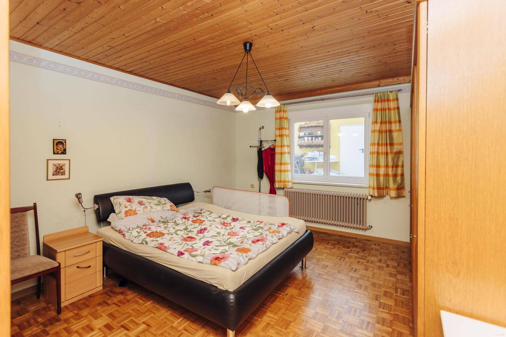 Gemütliches Schlafzimmer mit Holzbett, Parkettboden und Holzdecke, bietet eine warme Atmosphäre.