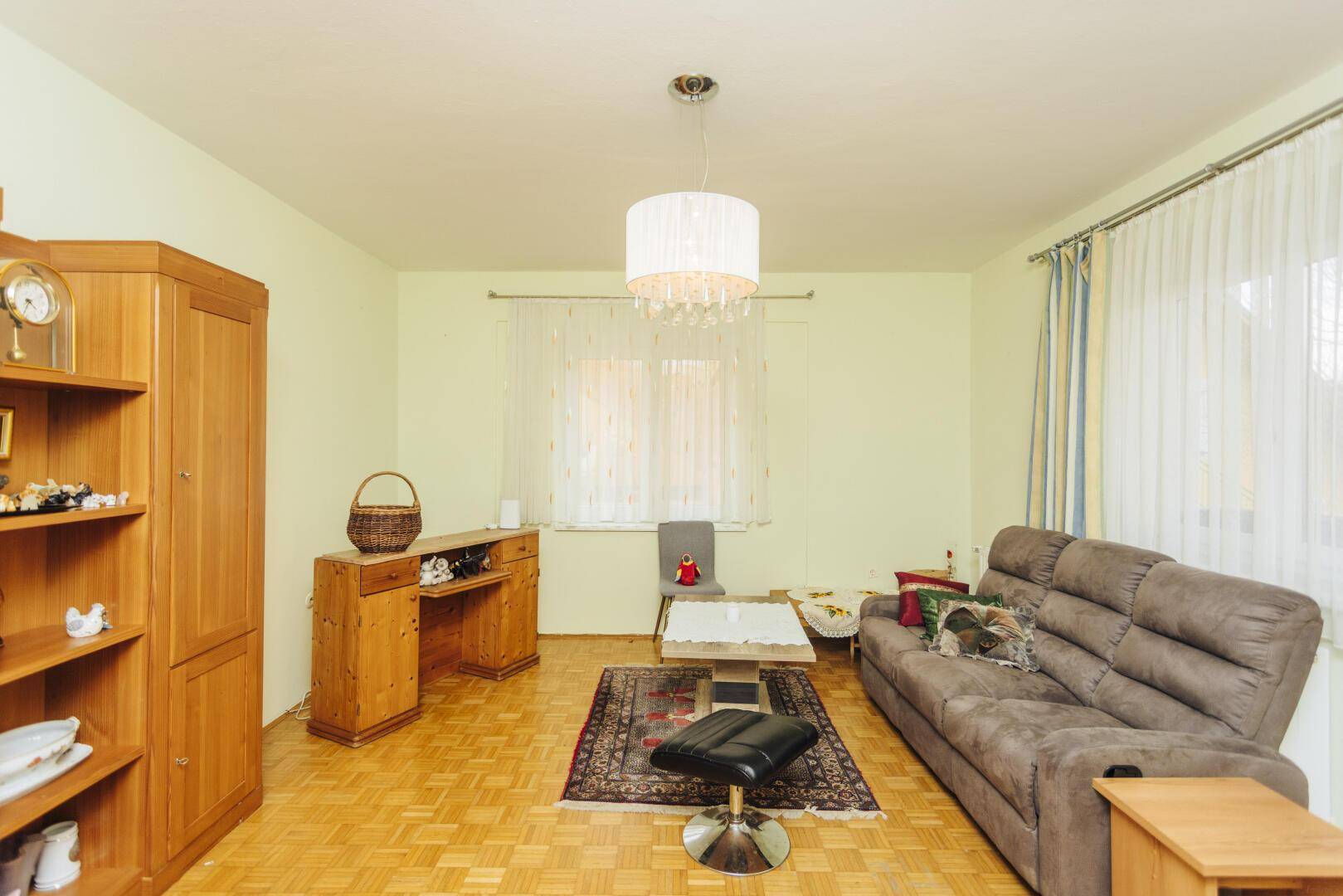 Helles Wohnzimmer mit bequemer Couch, Holzmöbeln und Parkettboden, ideal zum Entspannen.
