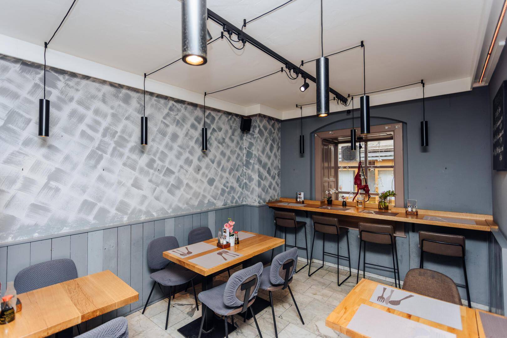 Heller Restaurantbereich mit Holztischen, bequemen Stühlen und dekorativer Wandgestaltung, die zum Verweilen einlädt.