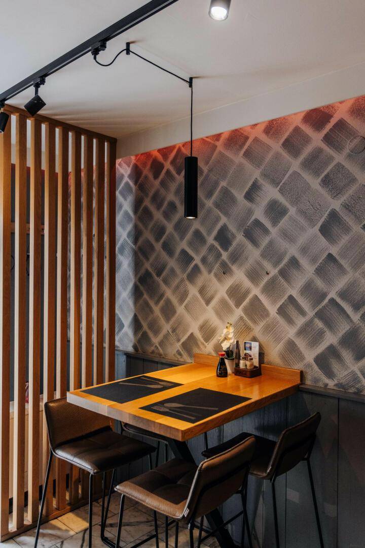 Detailansicht eines Tisches im Restaurant mit Barhockern und moderner Wanddekoration, die das Ambiente unterstreicht.
