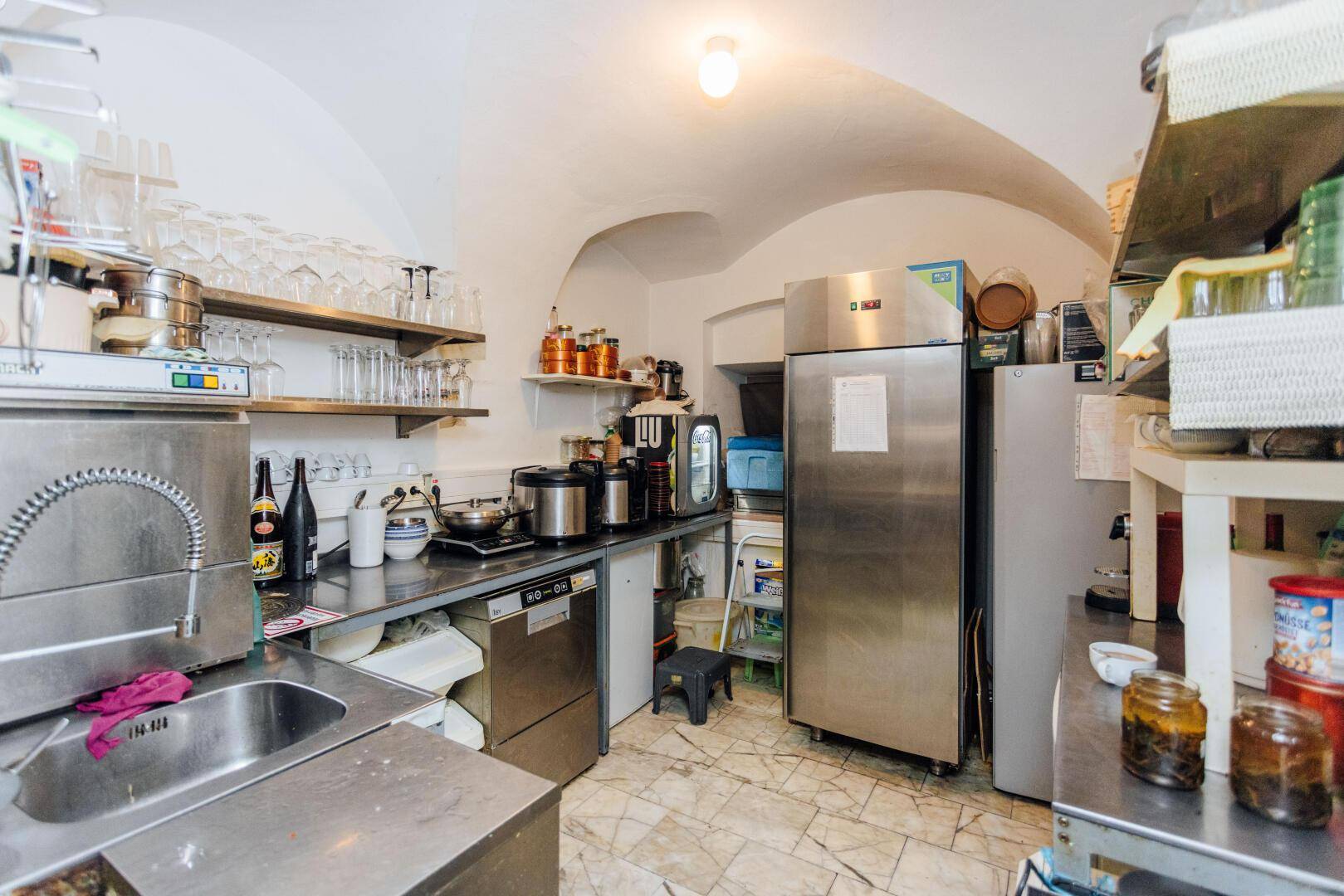 Professionelle Restaurantküche mit Edelstahlgeräten, Spülbecken und einer einzigartigen gewölbten Decke.
