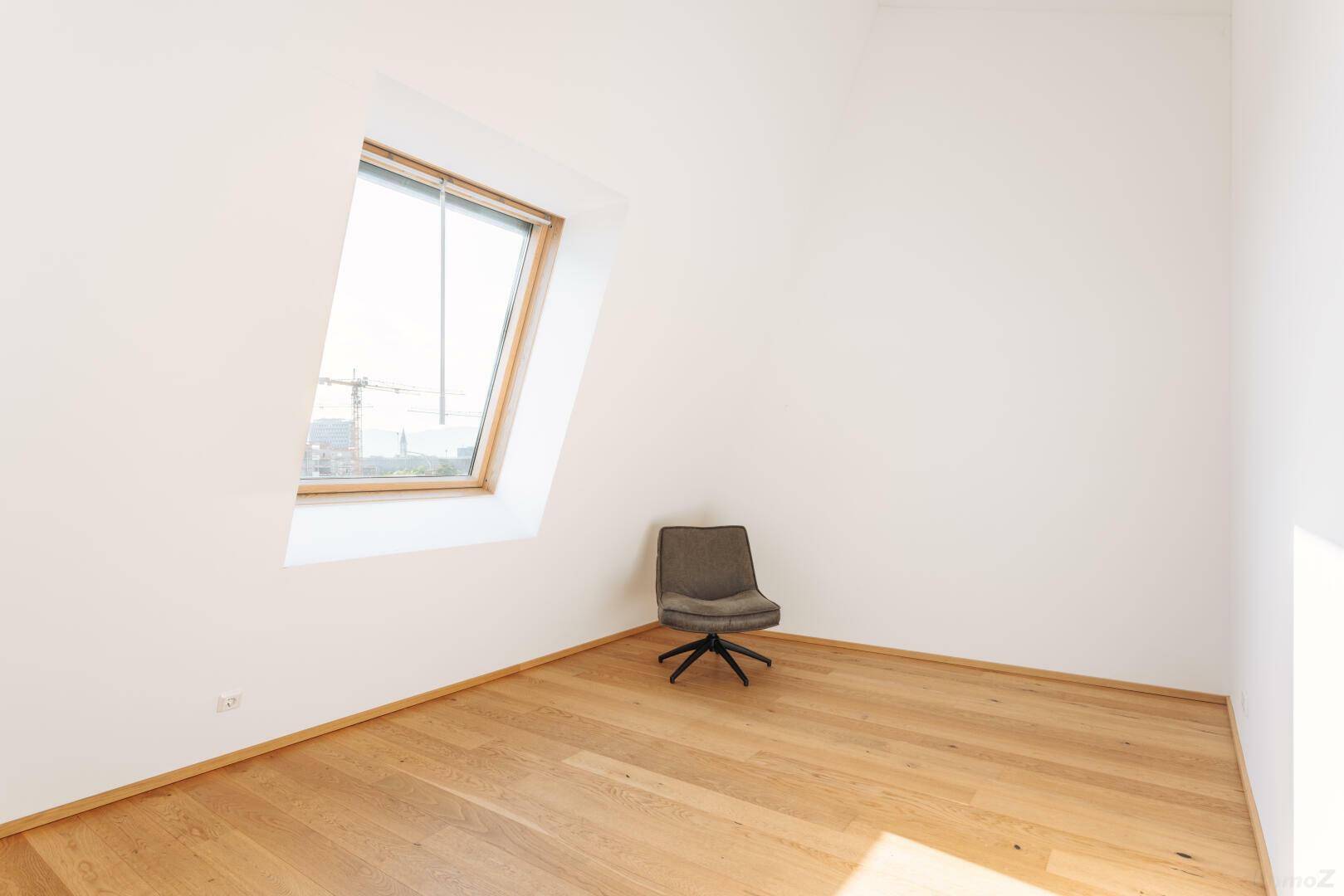 Heller Raum mit Holzboden und einem großen Dachfenster, ideal als Schlafzimmer oder Büro.