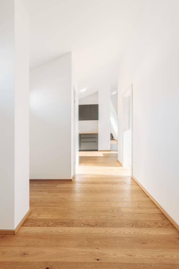 Heller Flur mit warmem Holzboden, der zu weiteren Räumen der Wohnung führt.