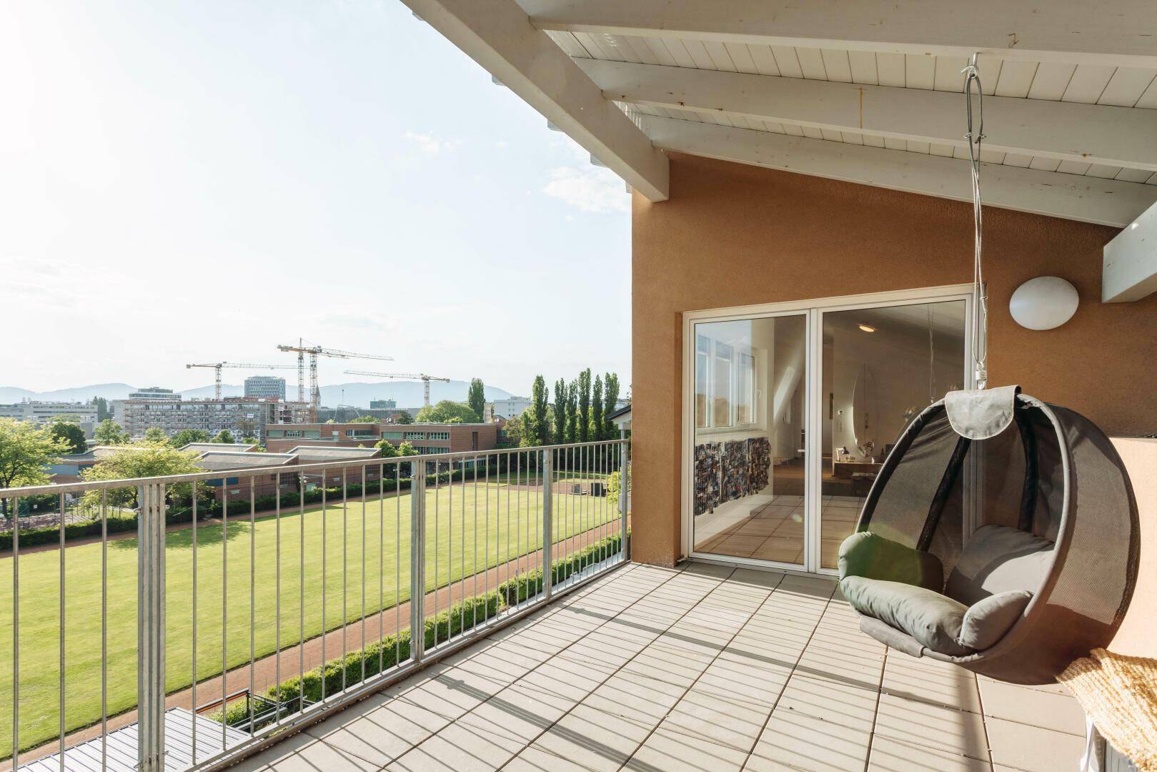 Geräumige Terrasse mit Weitblick über grüne Flächen und die städtische Kulisse.