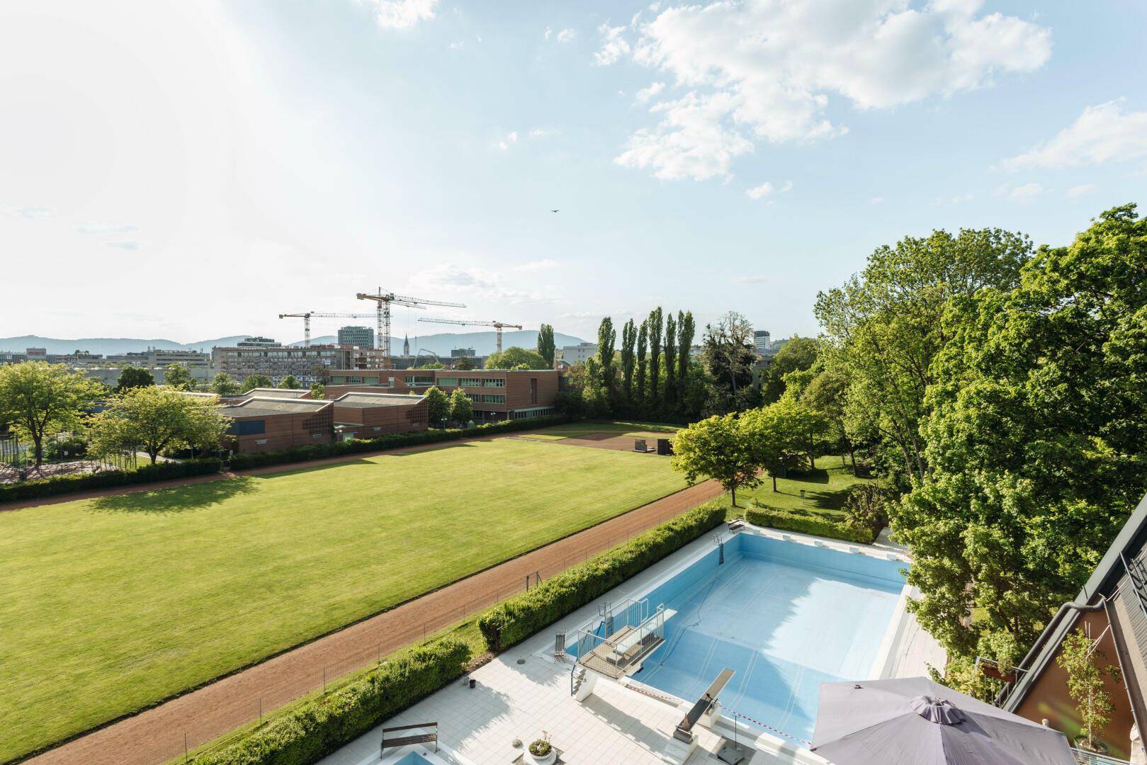 Aussicht von der Terrasse auf einen großen Außenpool und eine grüne Umgebung.