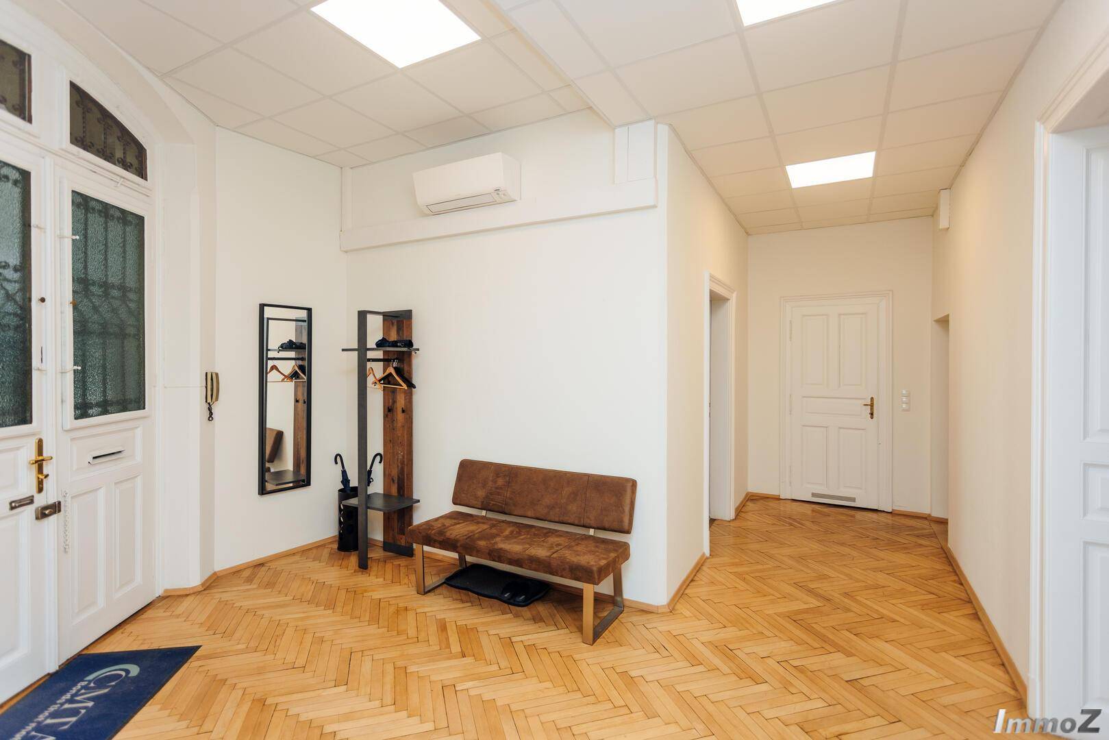 Geräumiger Eingangsbereich mit Fischgrätparkett, Garderobe und einer Sitzbank, bietet Komfort und Stauraum.