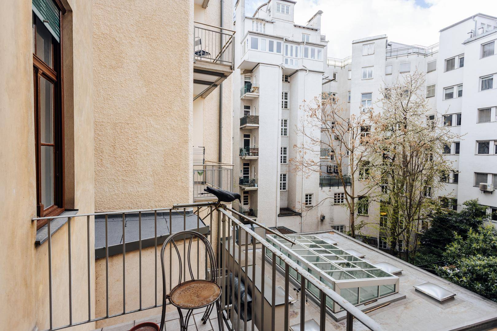 Kleiner Balkon mit Metallgeländer und Blick auf den Innenhof und umliegende Gebäude.