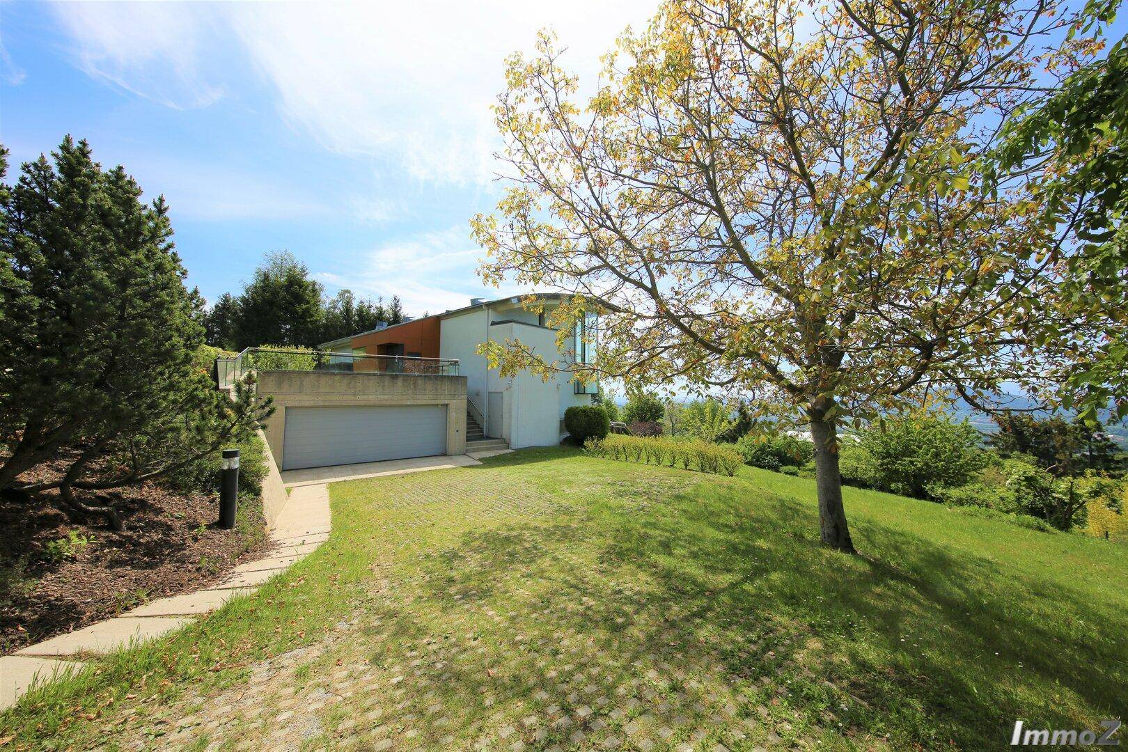 Großzügiger Gartenbereich mit Rasenfläche, Auffahrt und Blick auf das moderne Haus.