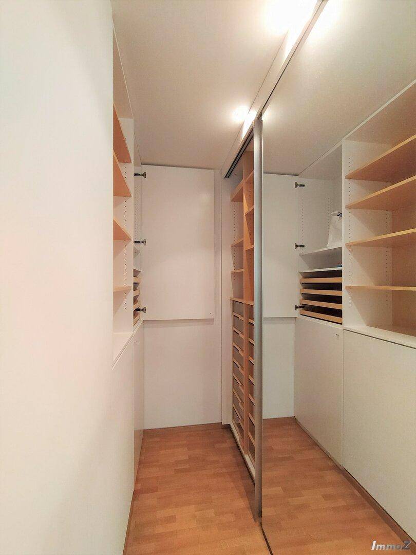 Geräumiger begehbarer Kleiderschrank mit vielen Regalen und Stauraum.