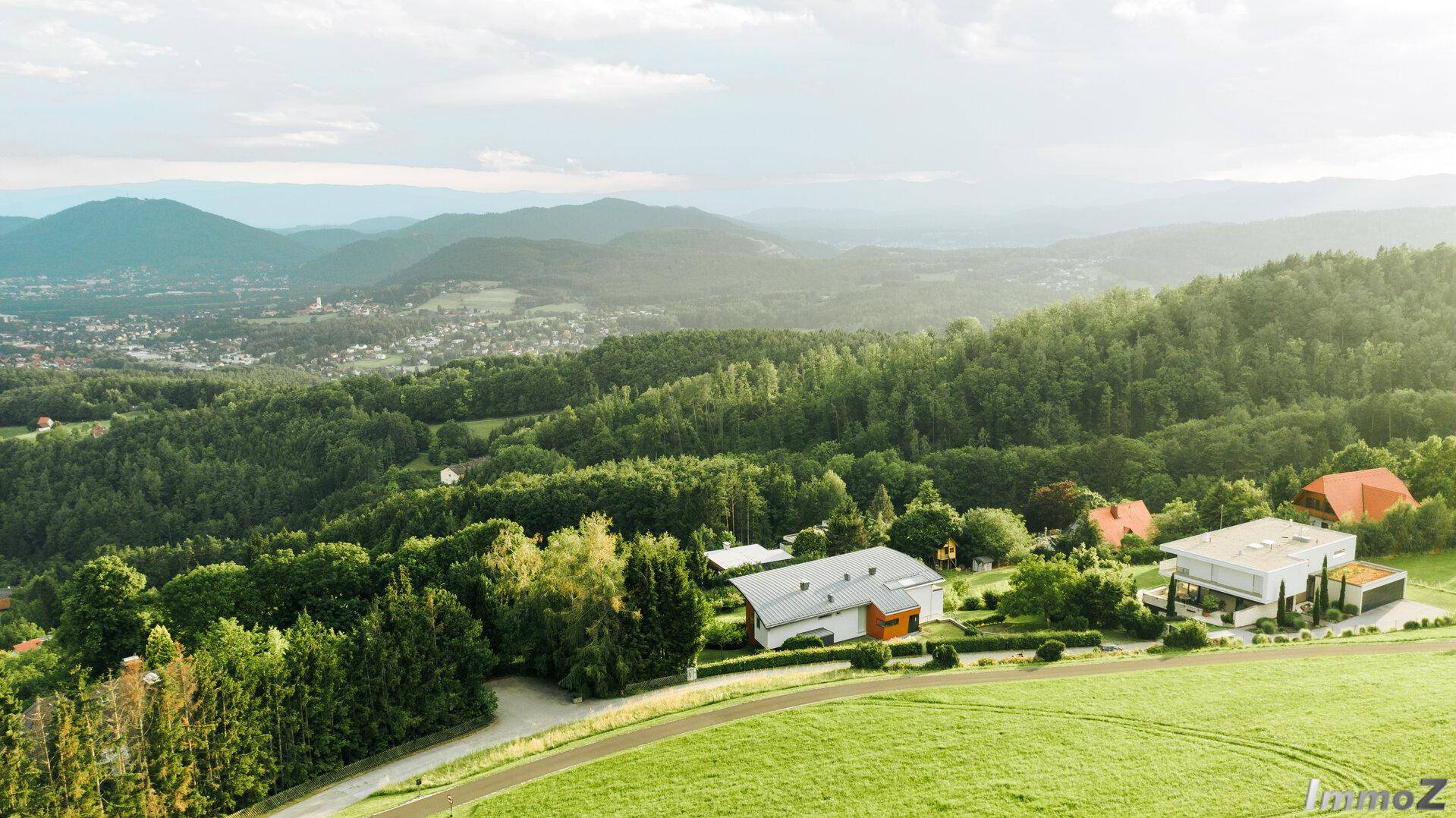 Luftaufnahme des Anwesens mit modernem Haus und weitem Blick über die bewaldete Landschaft.
