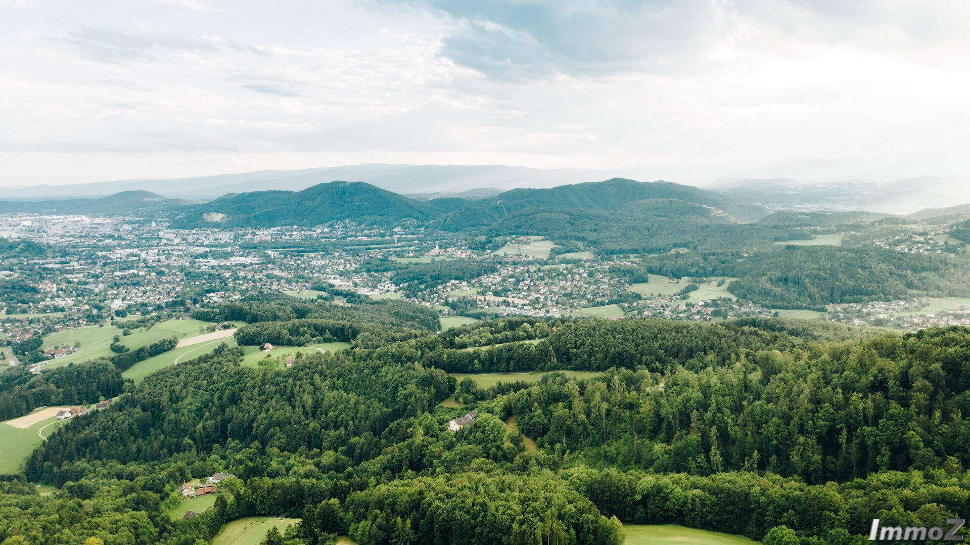 Panoramablick aus der Vogelperspektive über die grüne Landschaft und eine Stadt in der Ferne.