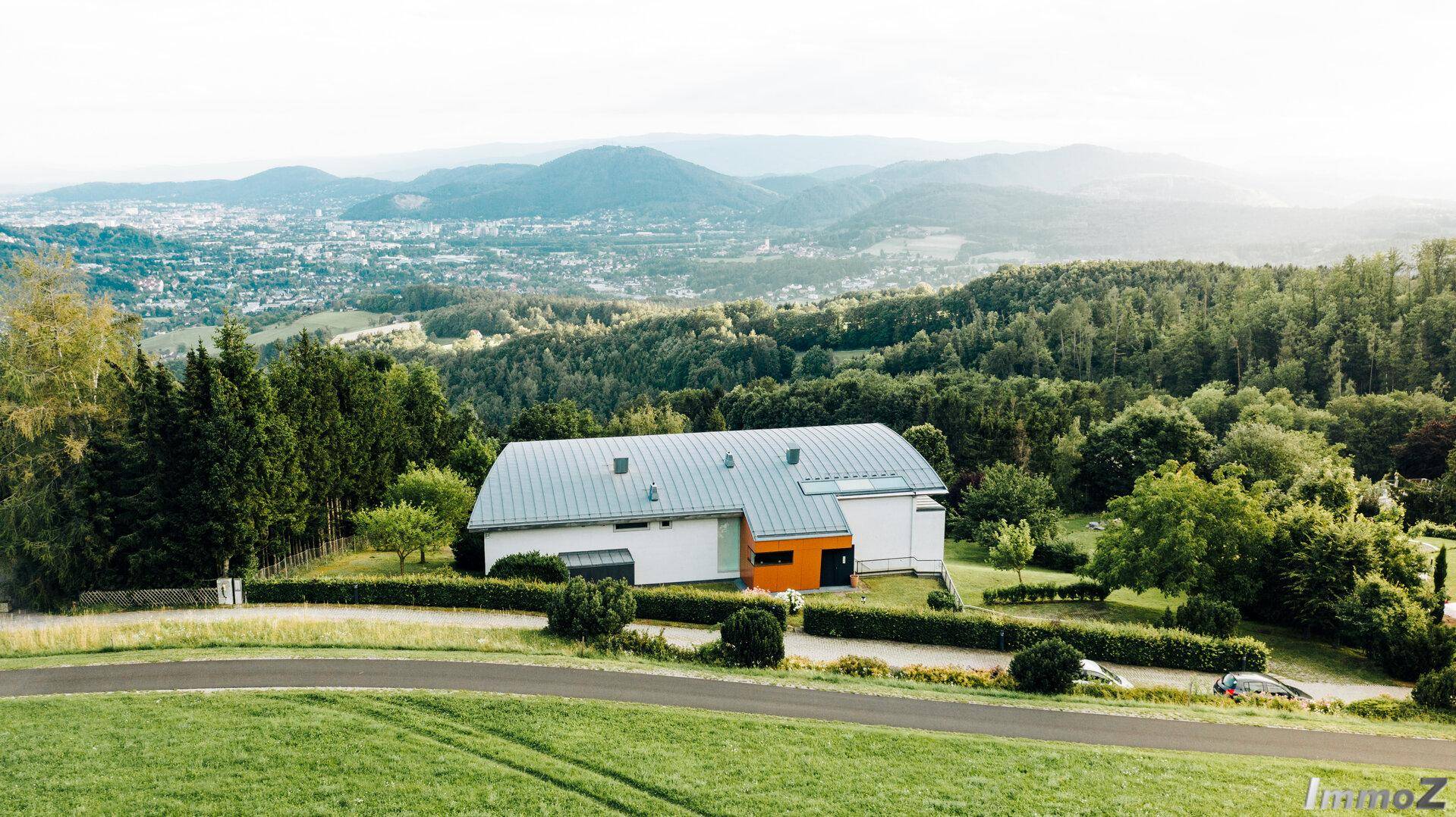 Luftaufnahme des modernen Hauses in idyllischer Hanglage mit weitem Blick über die Landschaft.