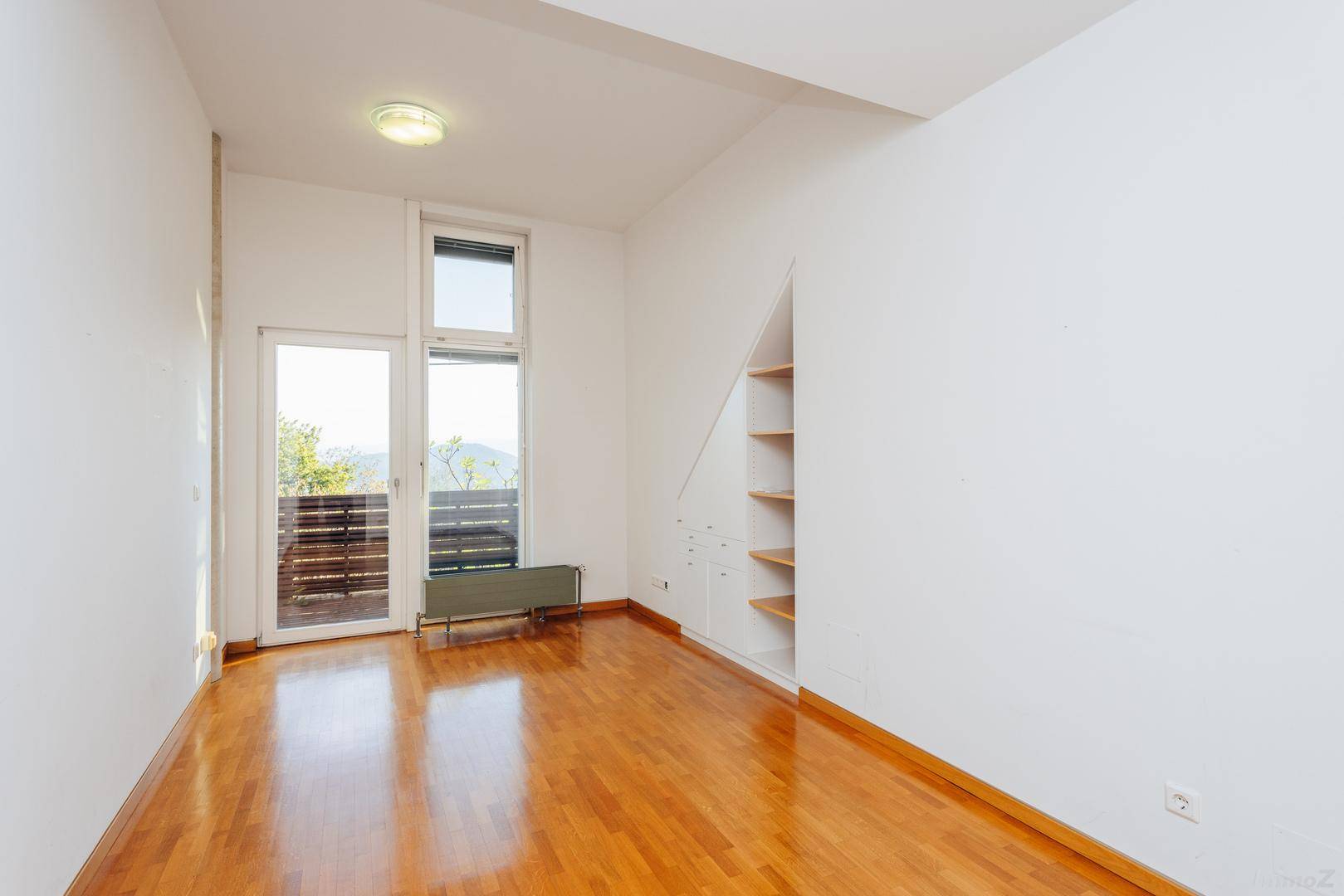 Helles Schlafzimmer mit Holzboden und Balkonzugang, bereit zur individuellen Gestaltung.