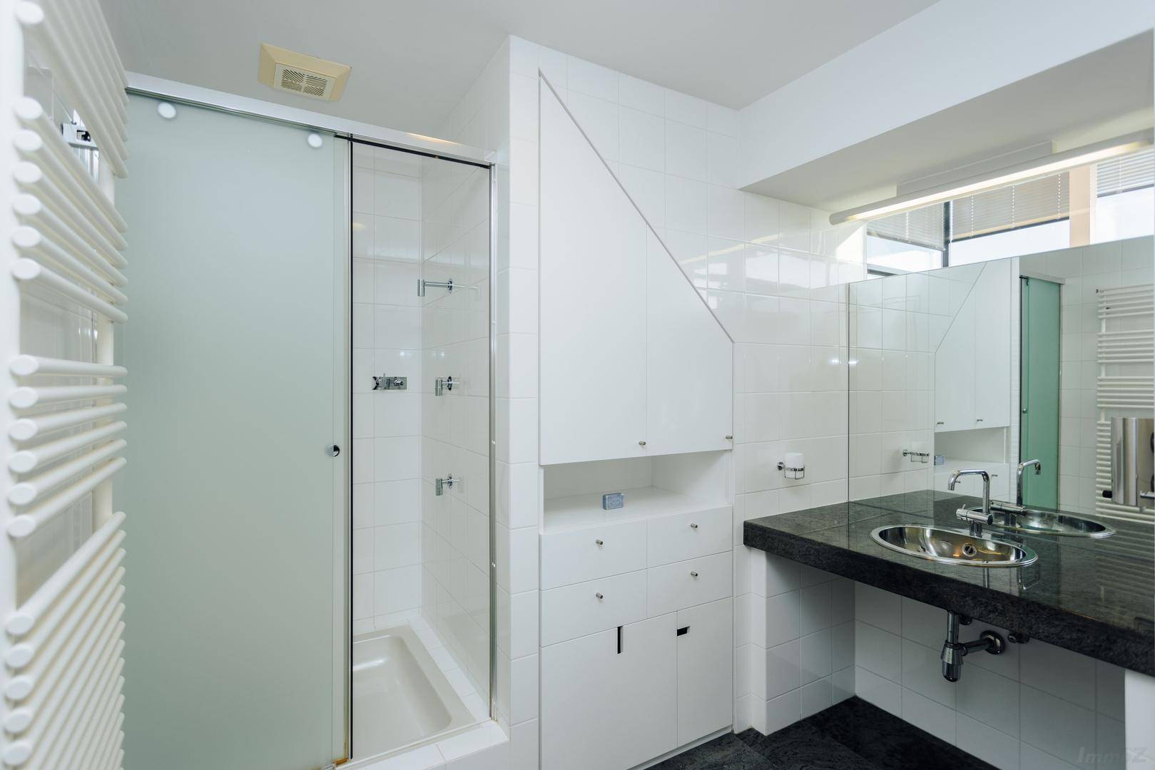 Modernes Badezimmer mit Doppelwaschbecken, Duschkabine und beheiztem Handtuchhalter.