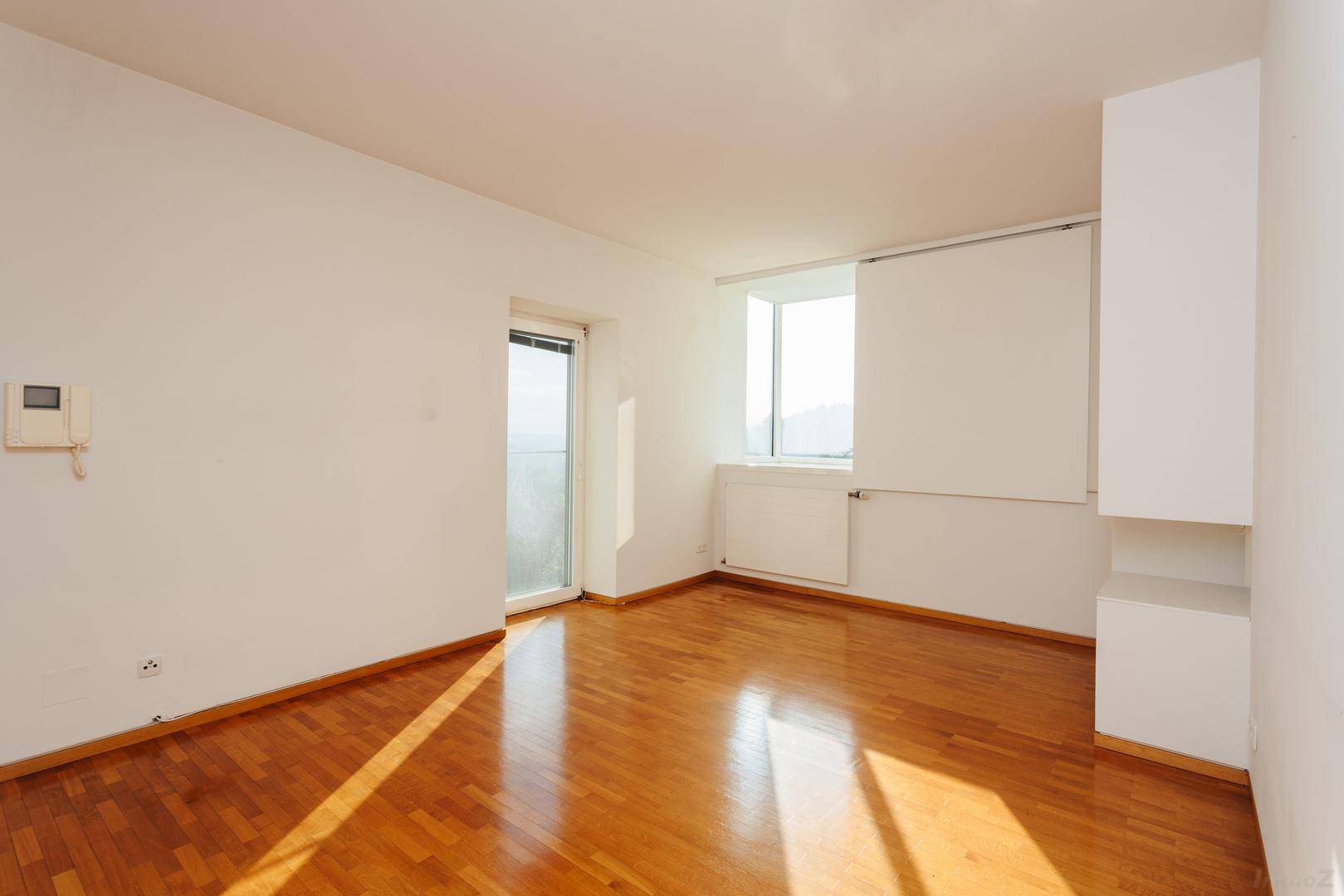 Helles Schlafzimmer mit Holzboden und Zugang zu einem französischen Balkon, bereit zur Einrichtung.