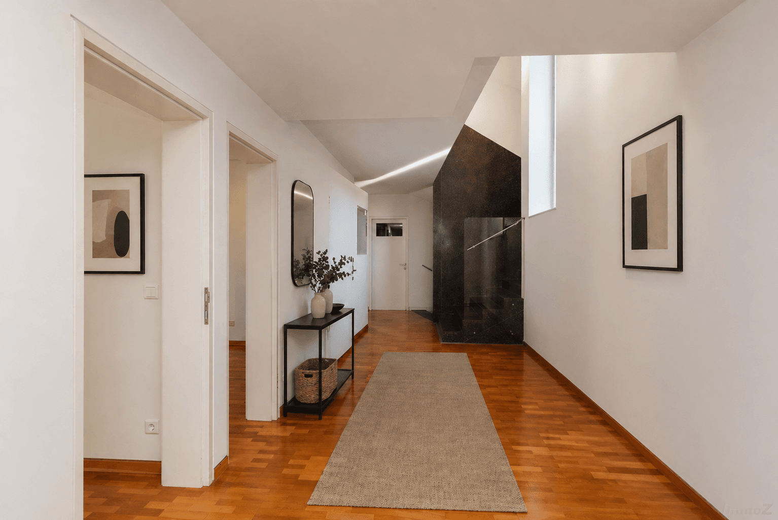 Heller Flur mit Holzboden, moderner Dekoration und Zugang zu weiteren Räumen.