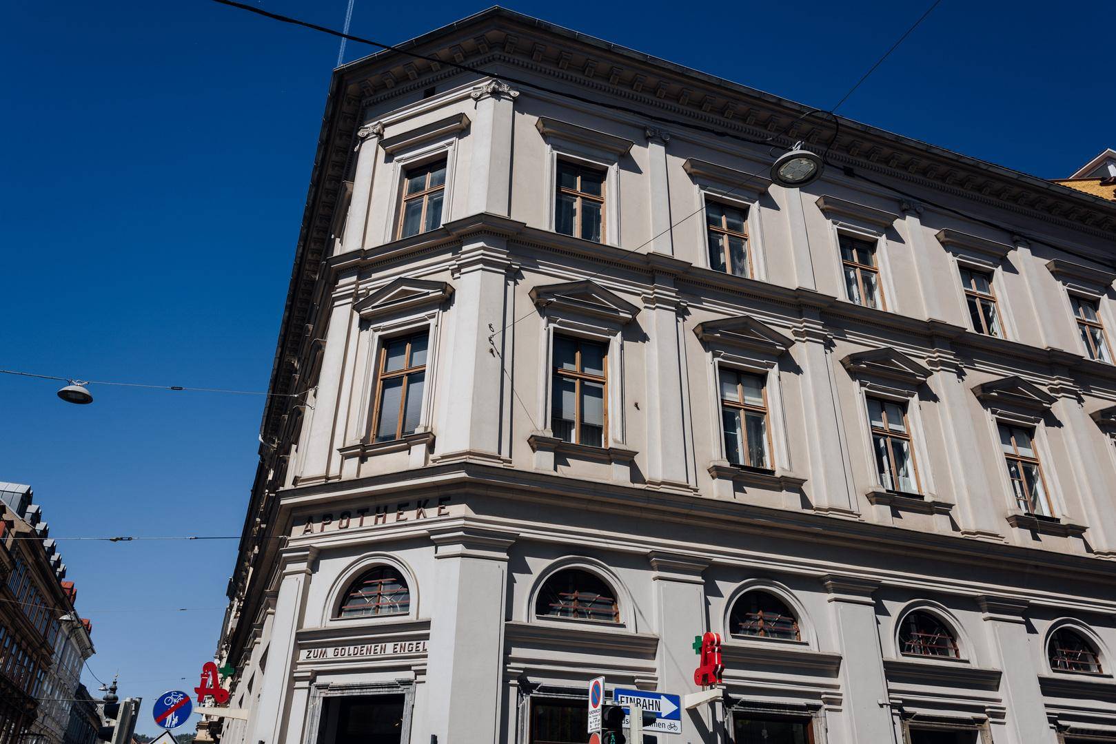 Historisches Eckgebäude mit Apotheke im Erdgeschoss und klassischer Architektur unter blauem Himmel.