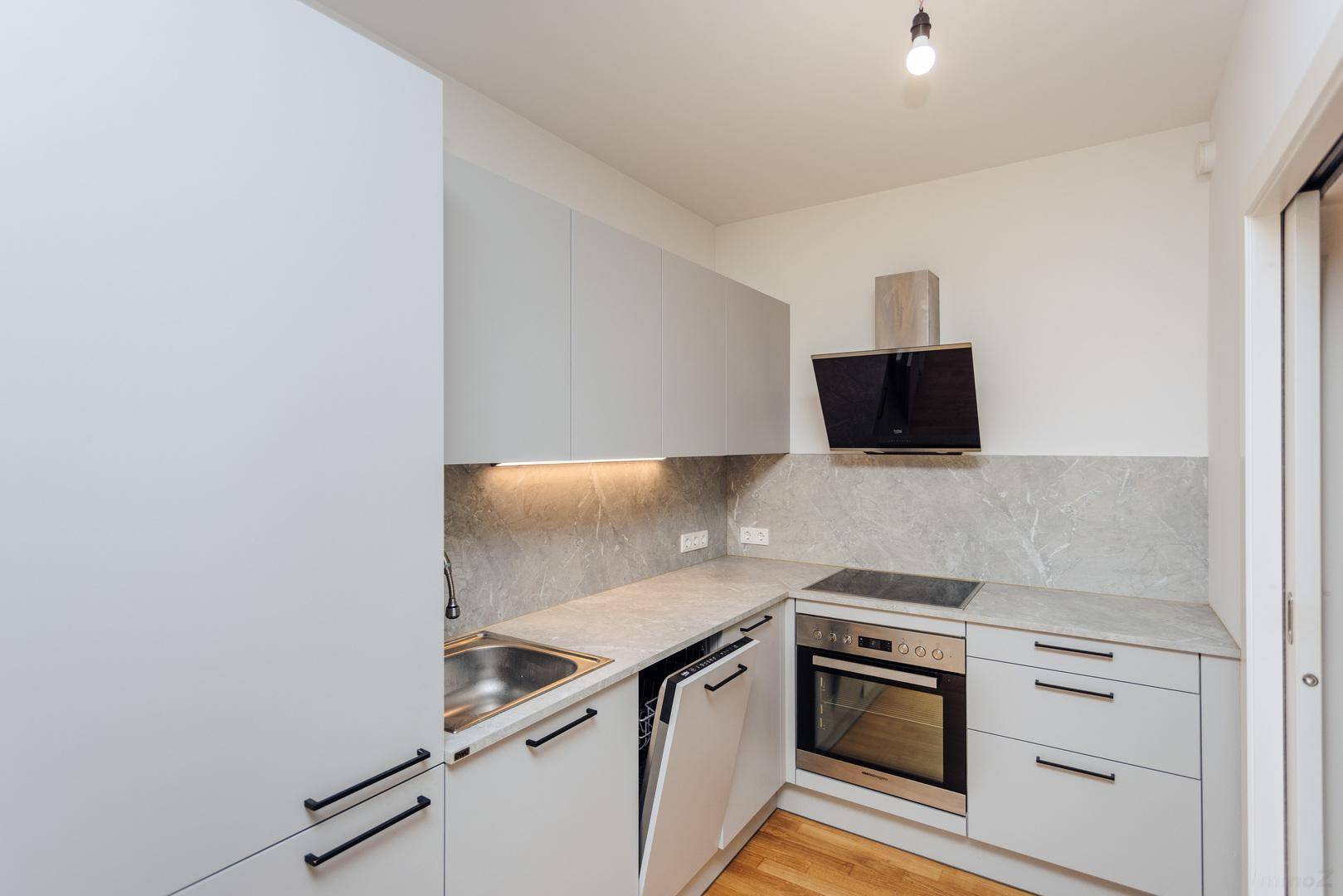 Moderne Einbauküche mit grauen Schränken, Steinoptik-Arbeitsplatte, Induktionskochfeld und integriertem Backofen.