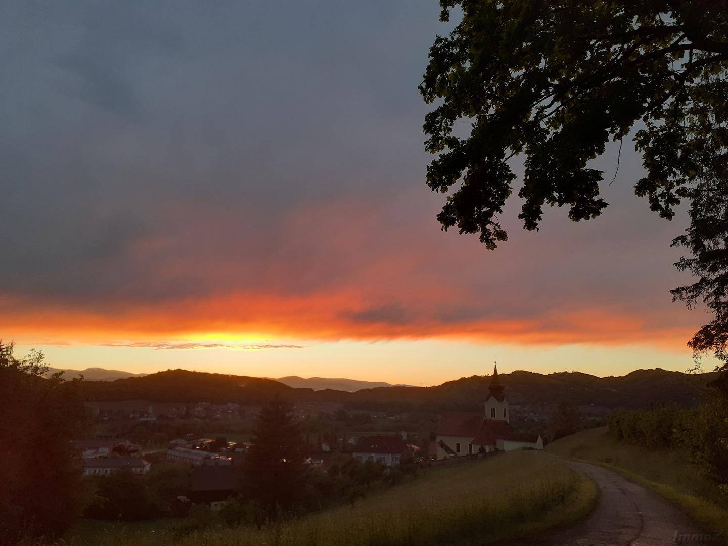 Spektakulärer Sonnenuntergang über einem ruhigen Dorf und den sanften Hügeln der Landschaft.