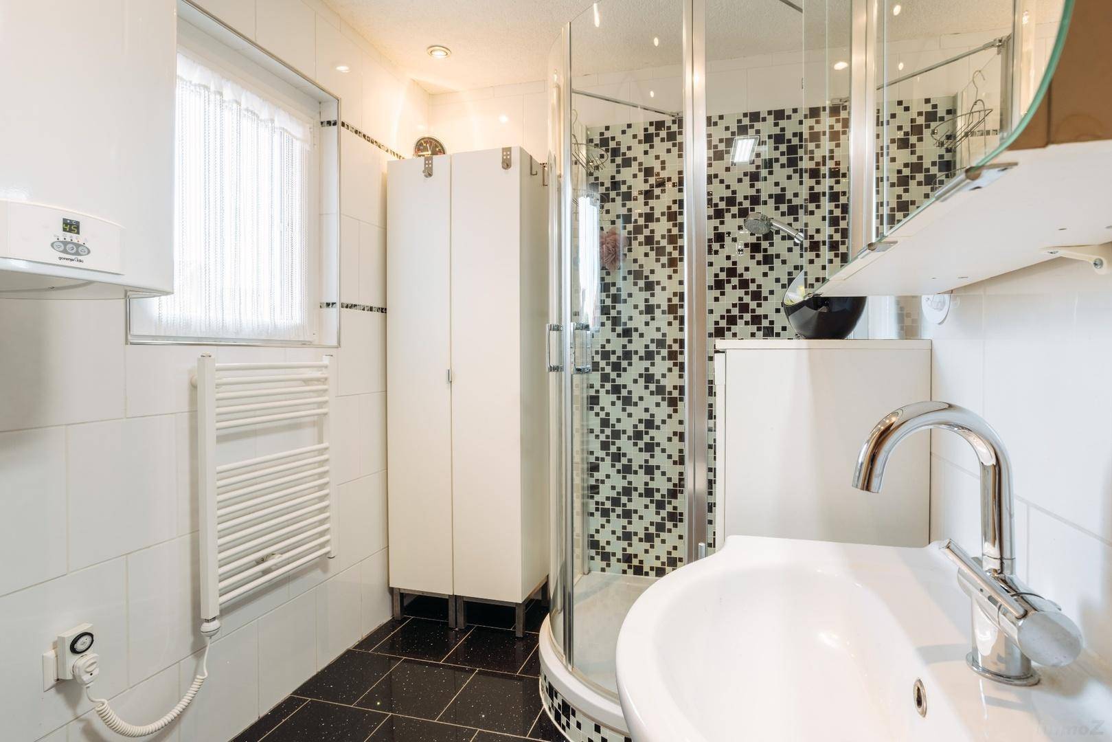 Modernes Badezimmer mit Duschkabine, Mosaikfliesen und beheiztem Handtuchhalter.