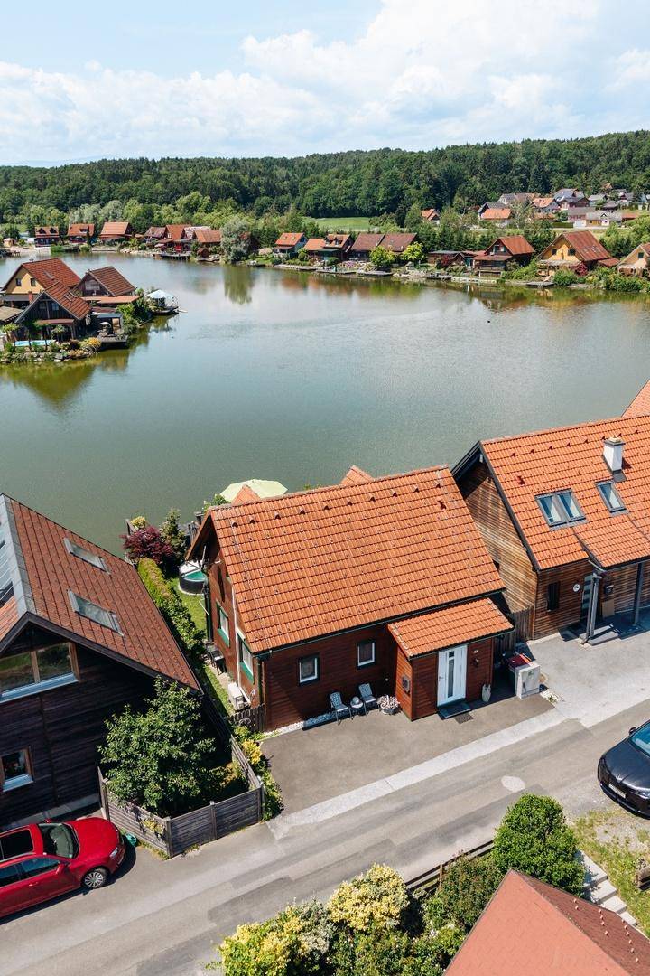 Luftaufnahme des Hauses mit Zufahrt und Seeblick, umgeben von weiteren Gebäuden und viel Grün.