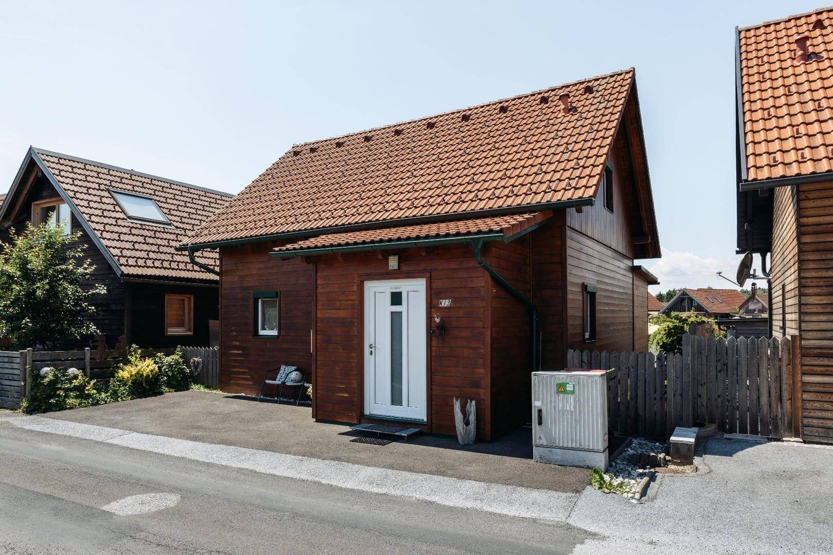 Vorderansicht eines charmanten Holzhauses mit Satteldach und gepflegtem Vorgarten an einer kleinen Straße.
