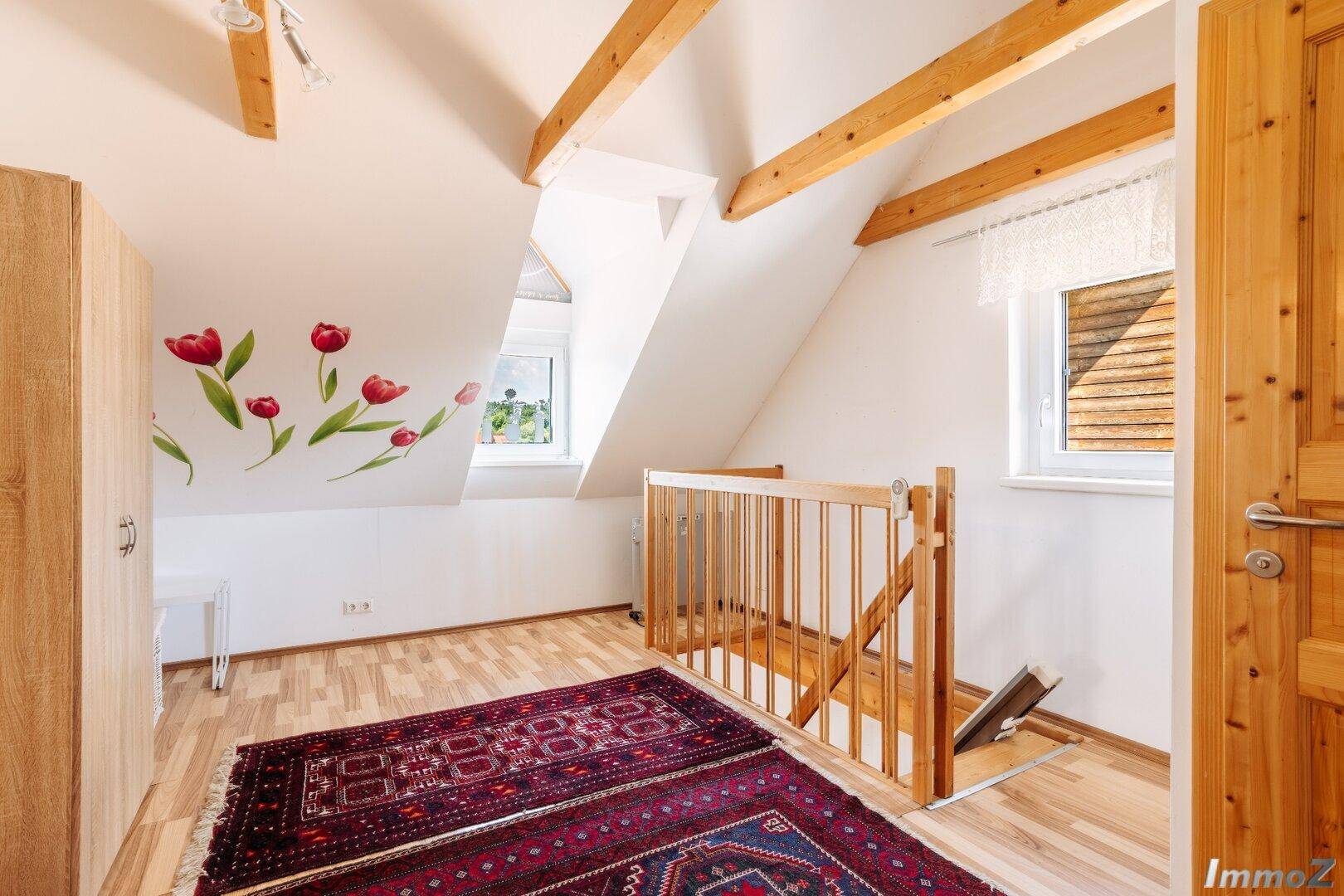 Heller Flur im Obergeschoss mit Holzboden, Treppe und dekorativen Wandstickern.
