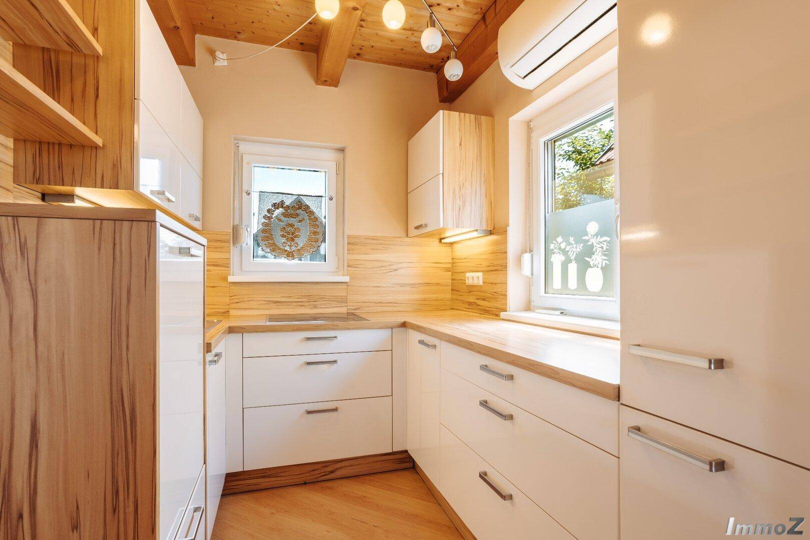 Moderne Küche mit hellen Holzfronten, Holzarbeitsplatten und sichtbaren Holzbalken an der Decke.