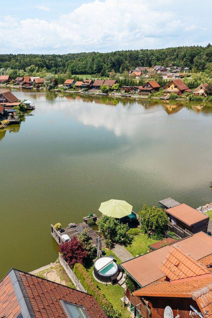 Luftaufnahme des Anwesens mit Seezugang, Whirlpool und Terrasse unter einem grünen Sonnenschirm.