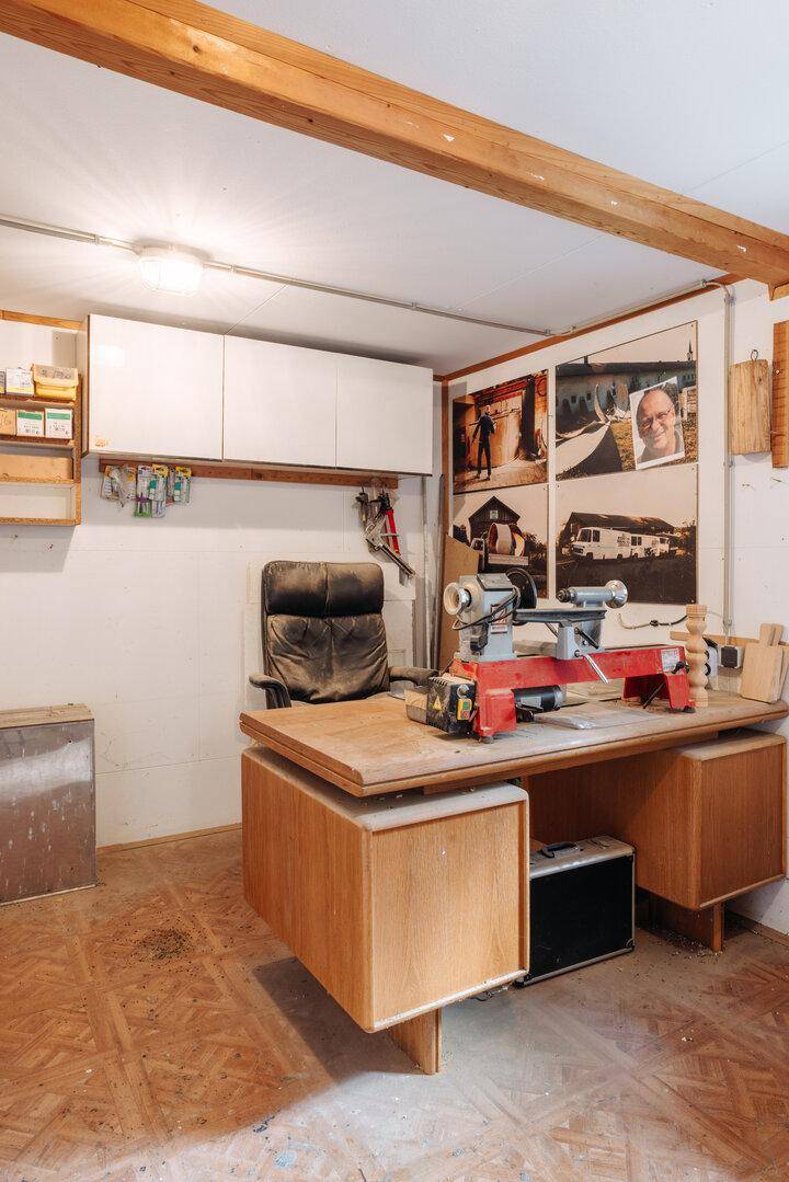 Kleiner Werkstattbereich mit Drechselbank, Schreibtisch und Regalen.