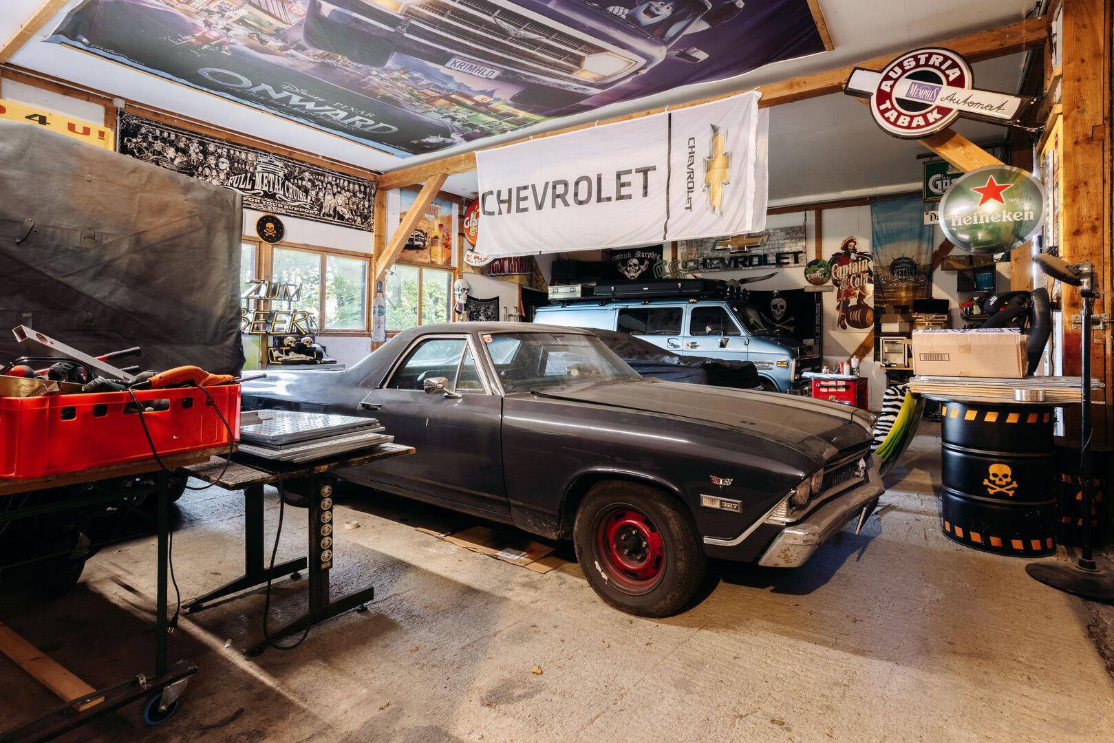 Geräumige Garage mit klassischem Auto, Werkstattbereich und rustikalen Holzbalken an der Decke.