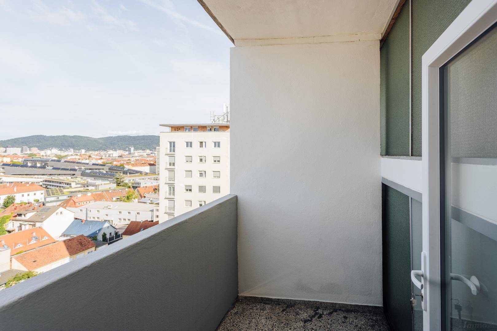 Heller Balkon mit niedriger Brüstung und weitem Blick über die Stadt und die Umgebung.