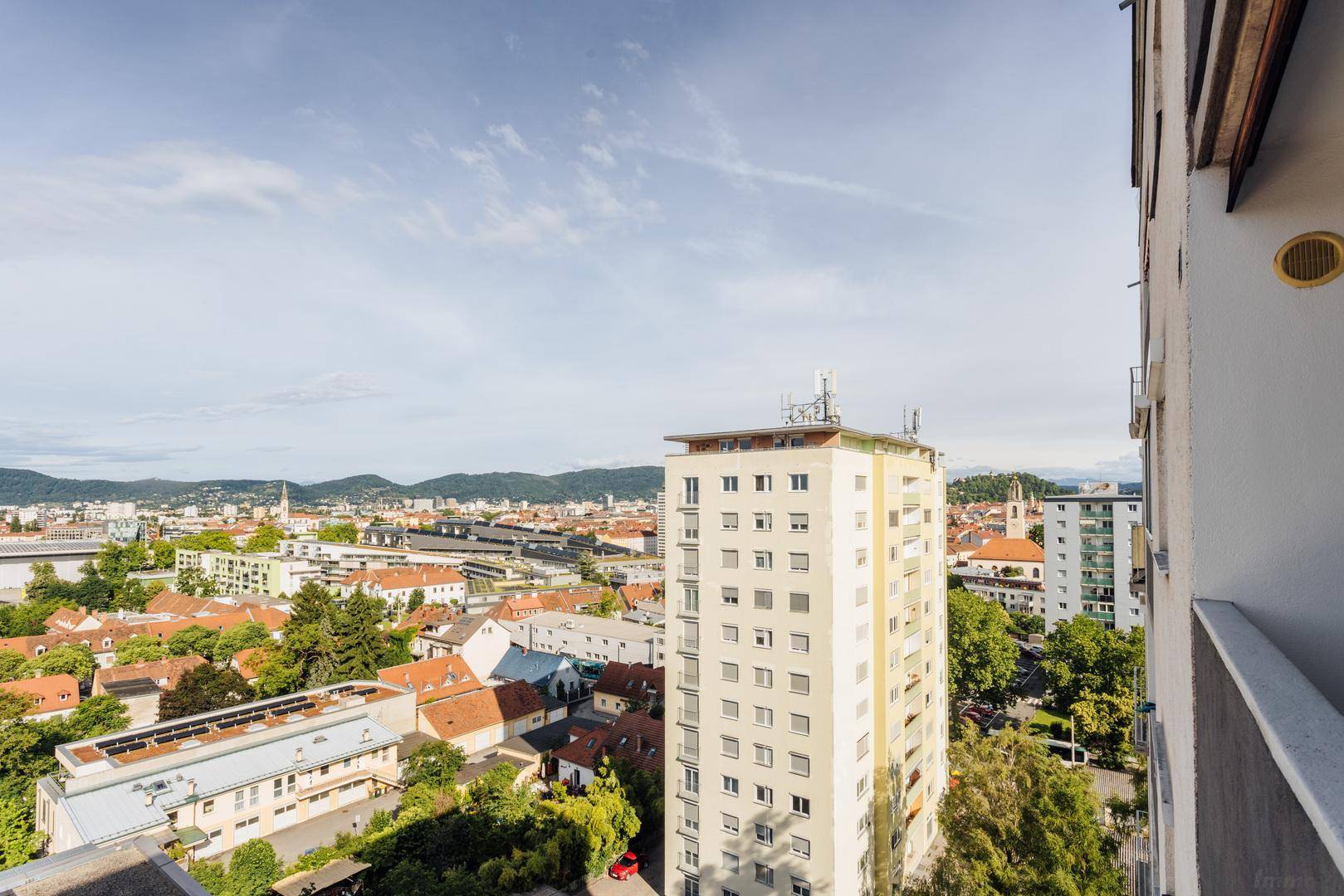 Weitblick vom Balkon auf ein hohes Wohngebäude und die umliegende Stadtlandschaft.