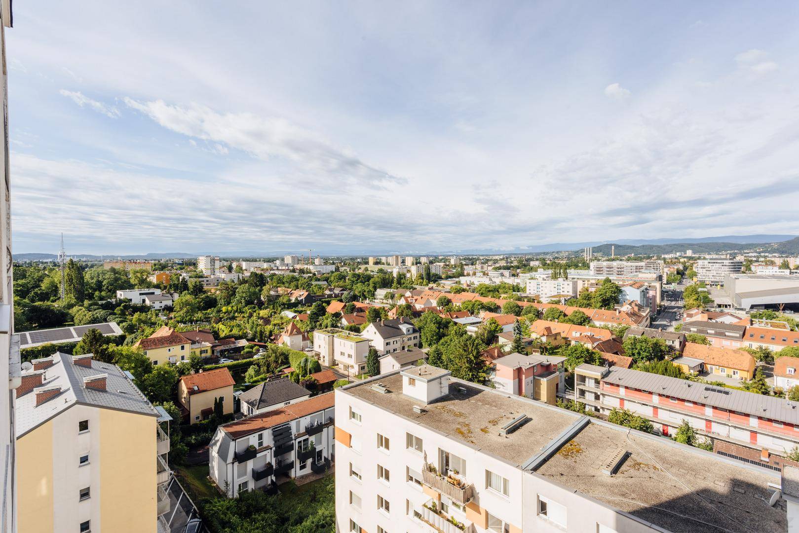 Ausblick vom Balkon auf eine ausgedehnte Stadtlandschaft mit Wohngebäuden und grünen Flächen.