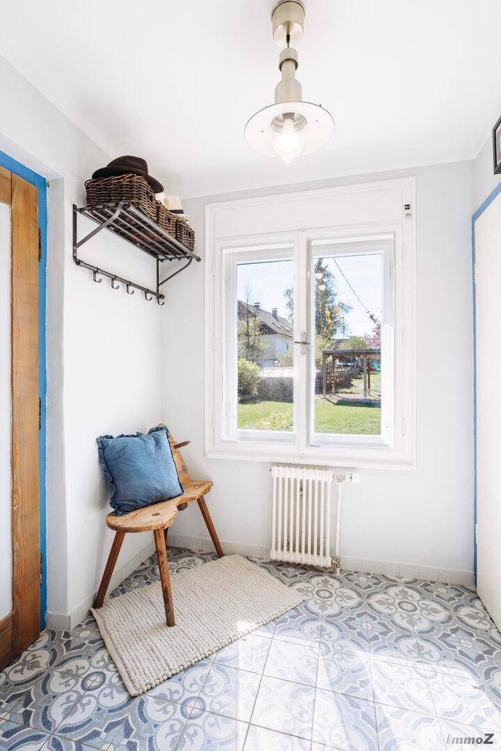 Heller Eingangsbereich mit gemustertem Fliesenboden, Garderobe und Fenster zum Garten.