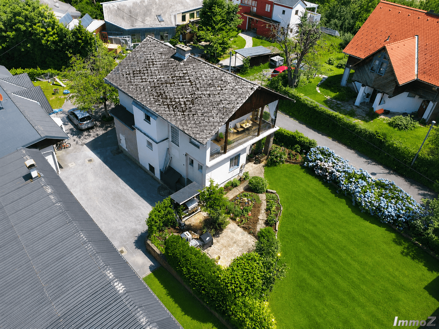 Luftaufnahme des Hauses mit gepflasterter Terrasse, Rasenfläche und angrenzendem Nebengebäude.