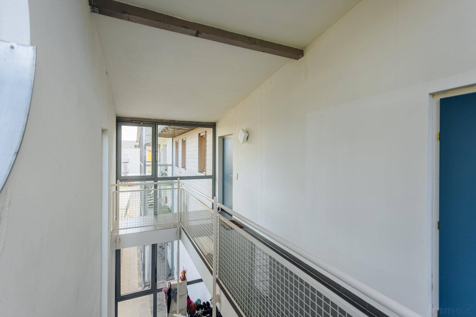 Helles Treppenhaus mit Glasfassade und Metallgeländer, das die verschiedenen Ebenen verbindet.