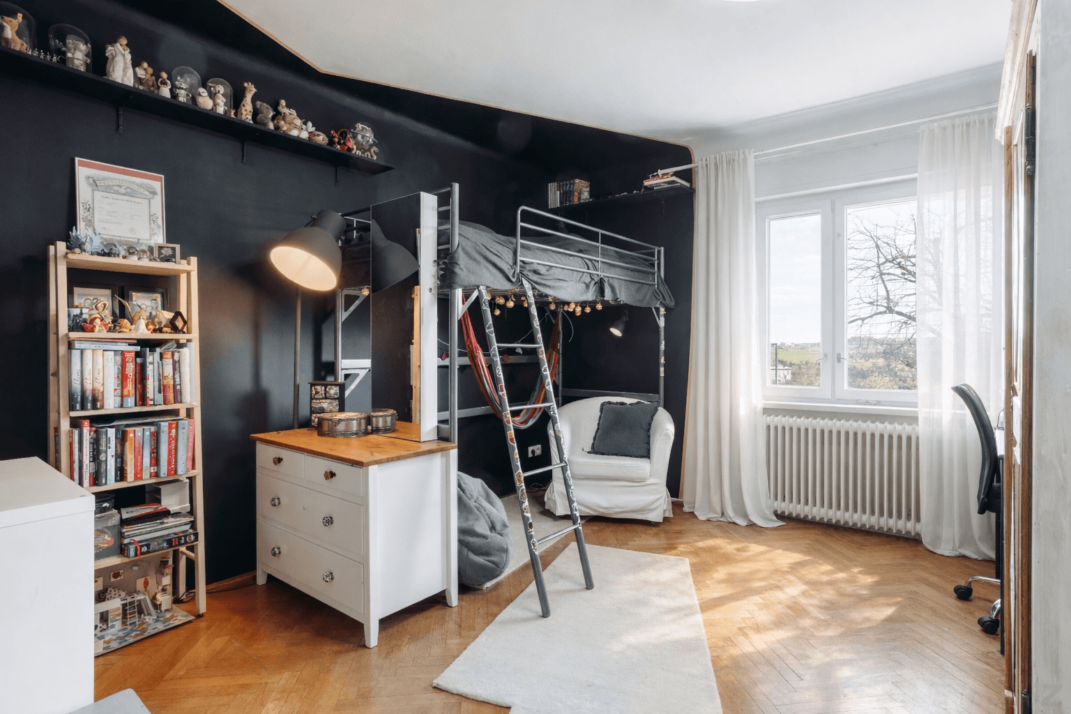 Jugendzimmer mit Hochbett, Schreibtisch und dunkler Akzentwand, funktional eingerichtet.